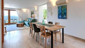 Uma sala de estar moderna com área de jantar, janelas amplas e vista para o exterior.