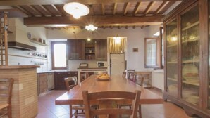 A spacious kitchen with a long wooden table, wooden chairs, and a built-in oven. - Torregentile by Interhome (Todi)
