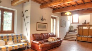 A cozy living room with a brown leather sofa, a plaid sofa, and a wooden staircase. - Torregentile by Interhome (Todi)