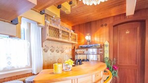 A wooden interior with a curved bar area, wooden cabinets, and a large door.