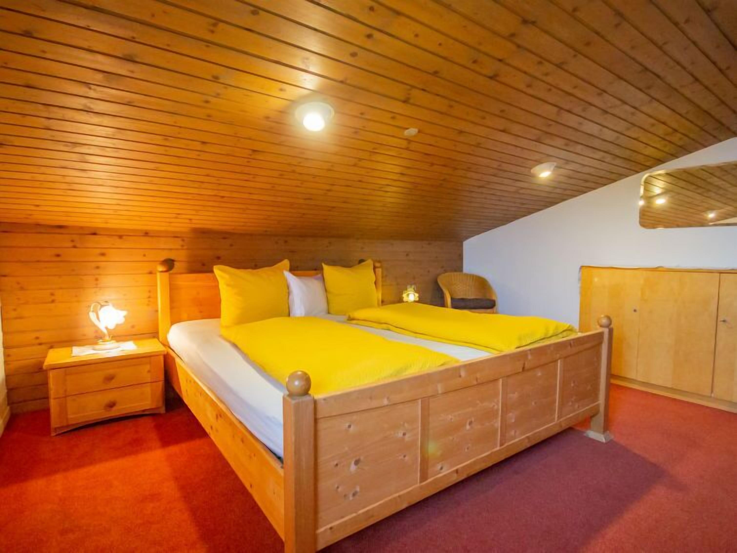 Un dormitorio de madera con cama, mesitas de noche y armario.