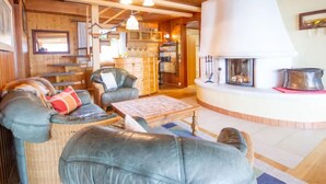 A cozy living room with a fireplace, leather sofas, and a wooden ceiling.