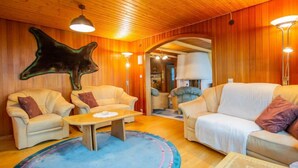 A cozy room with wooden walls, a large animal head decoration, and two sofas with cushions.