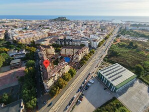 Vista aérea de un paisaje urbano con un edificio destacado que cuenta con piscina, rodeado de construcciones residenciales y comerciales.