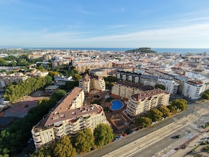 An aerial view of a cityscape with a prominent building featuring a swimming pool, surrounded by other residential and commercial structures.