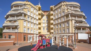 A multi-story residential building with balconies and a children's playground in front. - Jardines del Montgo by Interhome (Dénia)