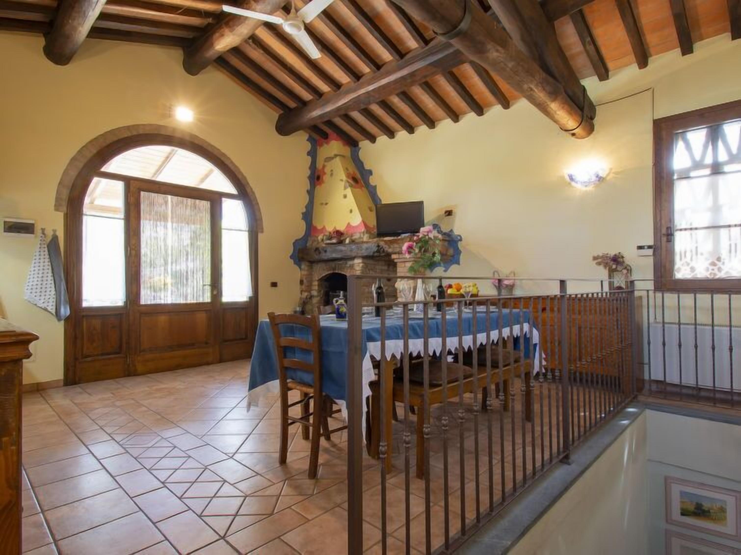 A dining area with a rustic wooden ceiling, a stone fireplace, and a table set for two.