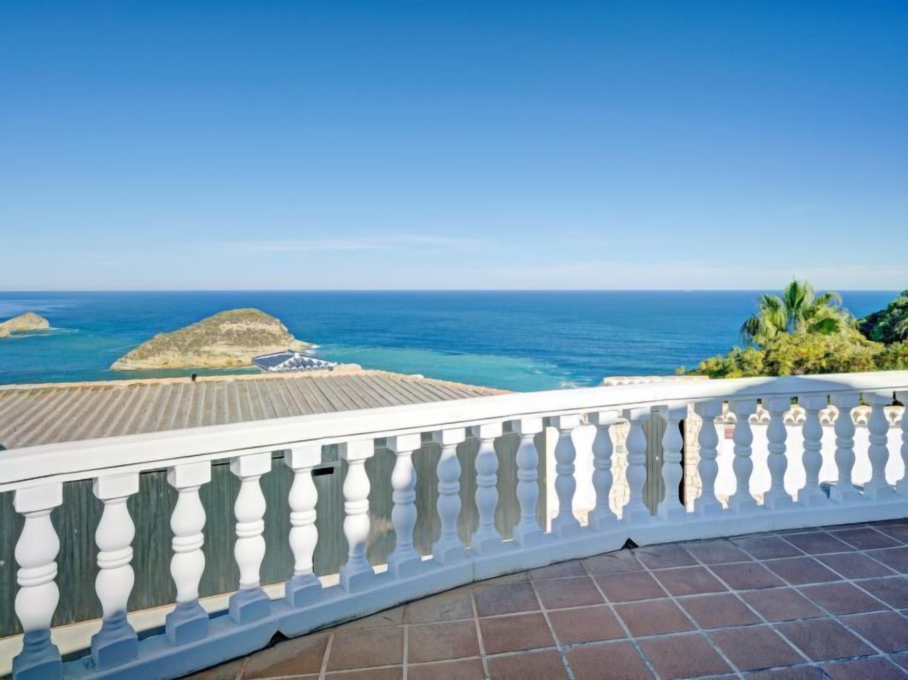 A balcony with a view of the ocean and rocky outcrops.