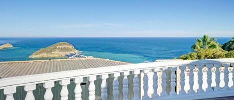 A balcony with a view of the ocean and rocky outcrops.