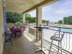 Un espacio exterior cubierto con piscina, una mesa con sillas y vista al mar.
