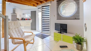 Un salon moderne avec un plafond en bois, un téléviseur, un canapé, une table basse et une plante en pot.