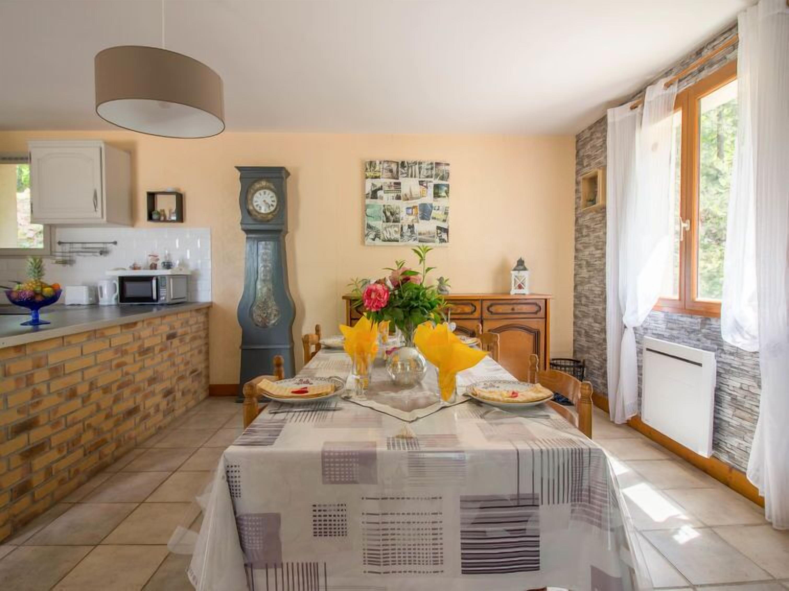 A dining area with a table set for two, a clock, and a wall with a collage of photos.