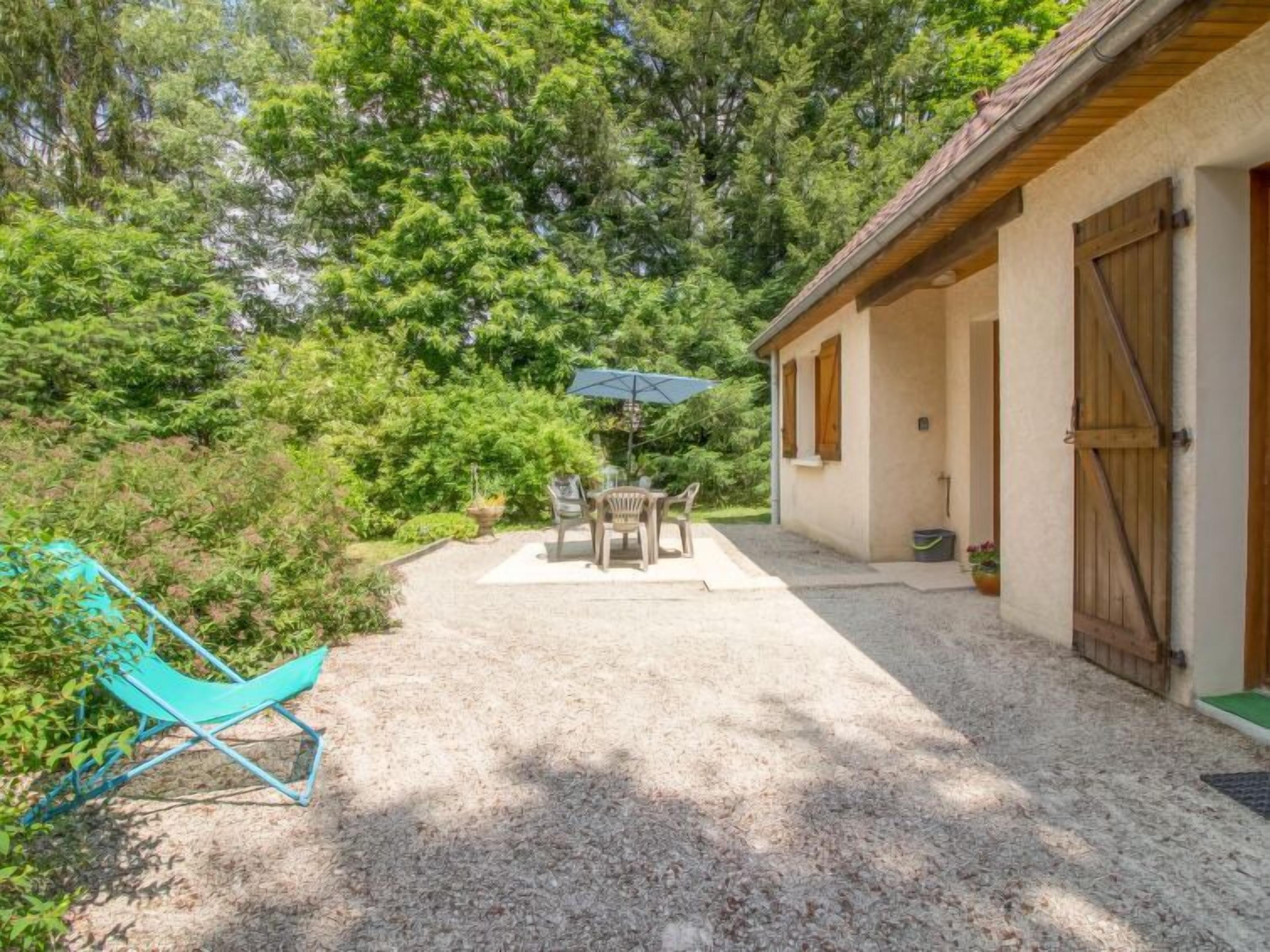 A covered patio with a table and chairs, a blue umbrella, and a turquoise lounge chair.