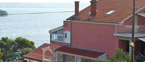 Un edificio residencial frente al mar, con techo de tejas rojas y balcón.