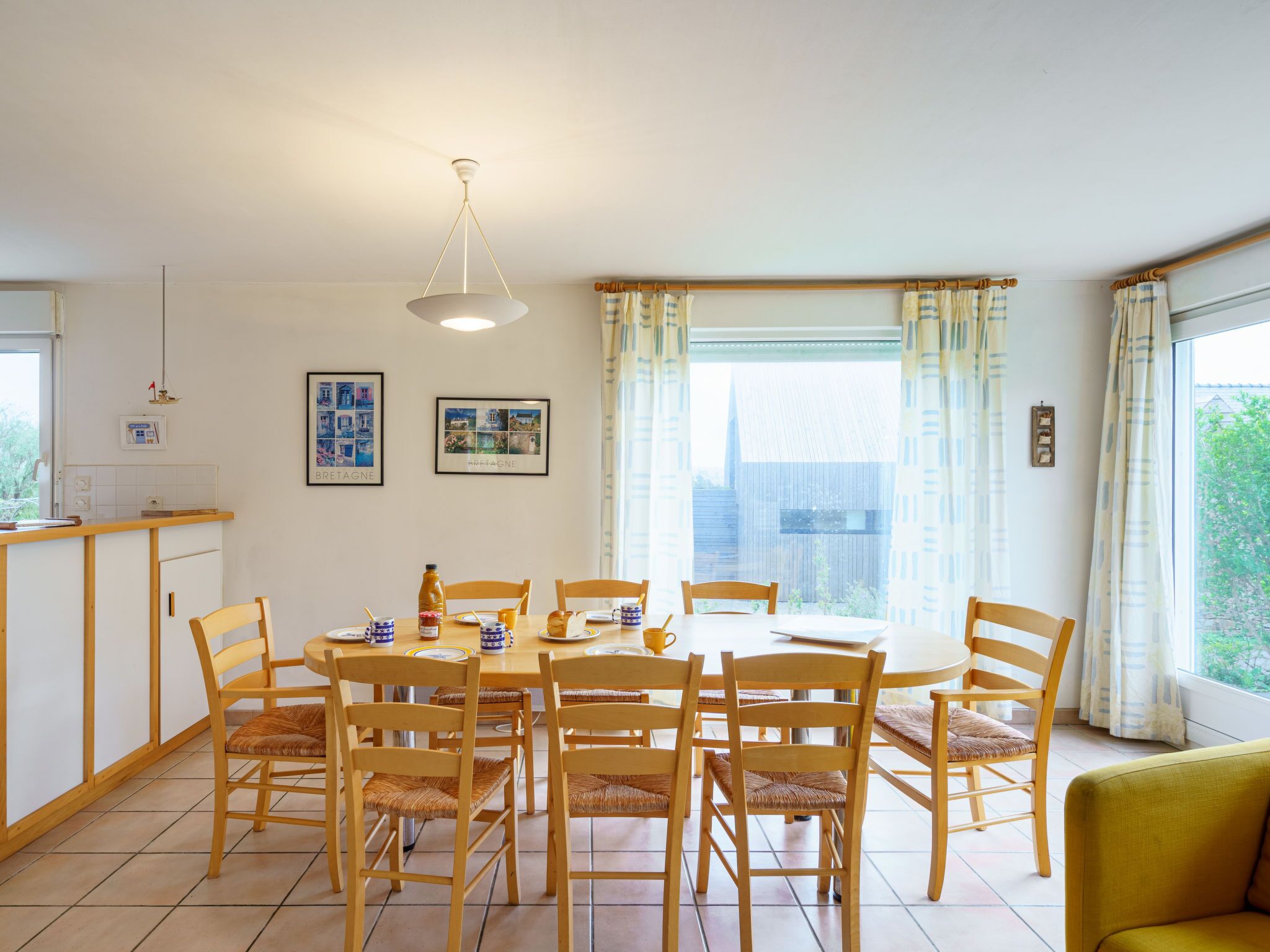 A dining area with a round table, wooden chairs, and a hanging light fixture.