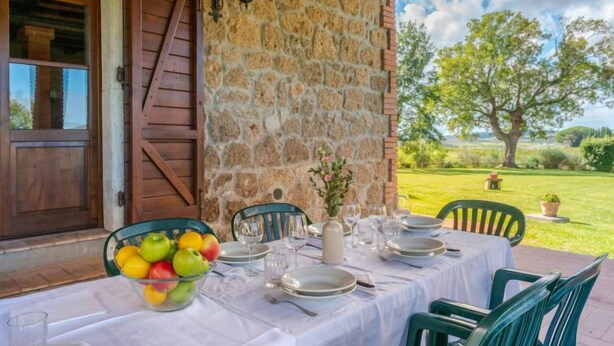 Pared de piedra con puerta de madera y mesa lista para comer, con sillas.