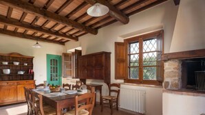 Comedor rústico con una mesa y sillas de madera, una puerta verde y una chimenea de piedra.