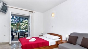 Un dormitorio con cama, sofá, televisor y balcón con sillas.