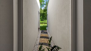 Ein moderner Flur mit geometrischem Bodenmuster, der zu einem Gartenbereich führt.