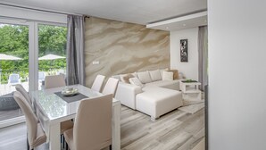 Ein modernes Wohnzimmer mit einem Glastisch, weißen Sofas und einer beige strukturierten Wand.