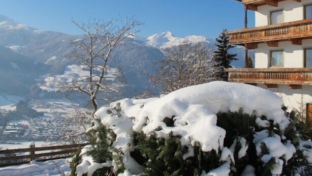 Un chalet de montagne doté d’un balcon en bois et offrant une vue sur des montagnes enneigées.