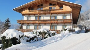 Un chalet en bois à plusieurs étages, doté de balcons, niché dans un paysage enneigé.