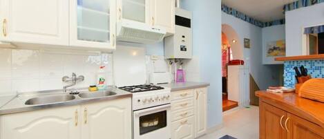 A kitchen with white cabinets, a gas stove, and a sink.