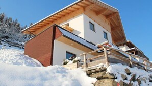 A modern two-story house with a sloped roof, wooden exterior, and a stone foundation. - Apartment Hanna by Interhome (Kaltenbach)