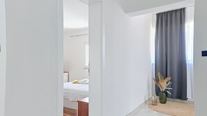Een hotelkamer met een bed, nachtkastje, spiegel en raam met gordijnen.