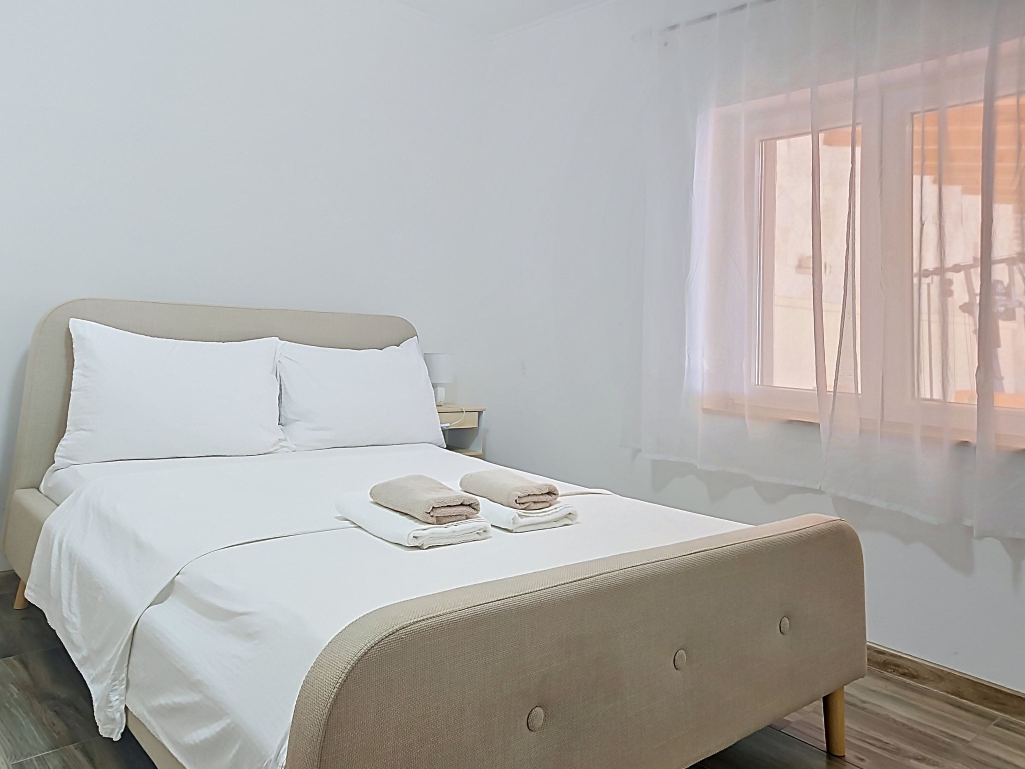 A bed with white linens, a headboard, and two towels on the bed.
