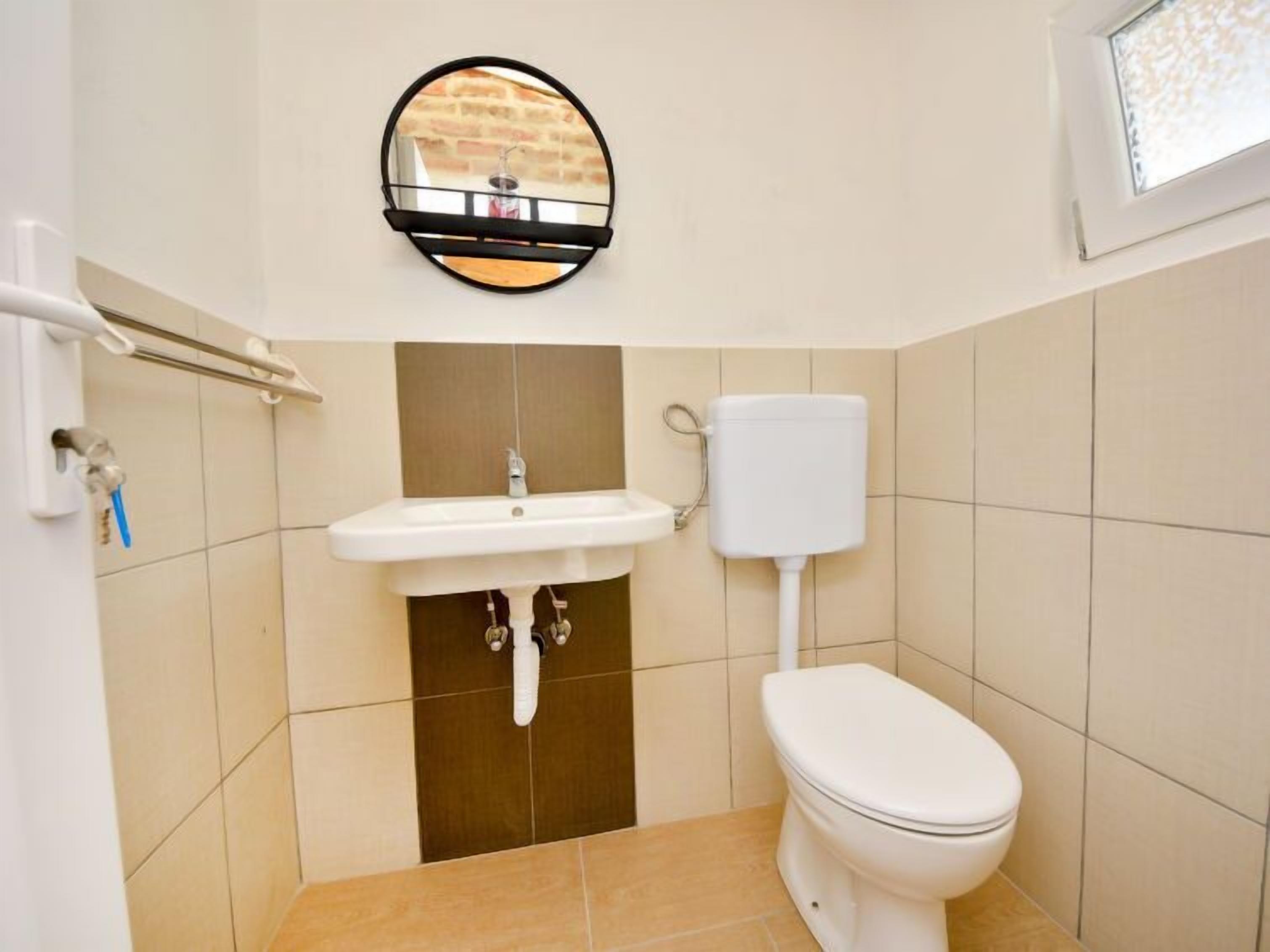 Une petite salle de bain avec un lavabo blanc, des toilettes et un miroir au mur.