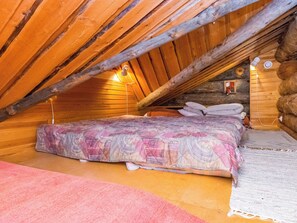 Quarto de sótão acolhedor, com cama, almofadas e uma pequena janela.