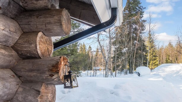 A log cabin with a snow-covered ground and a clear sky.