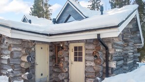 A log cabin with a snow-covered roof and two doors, one with a window.