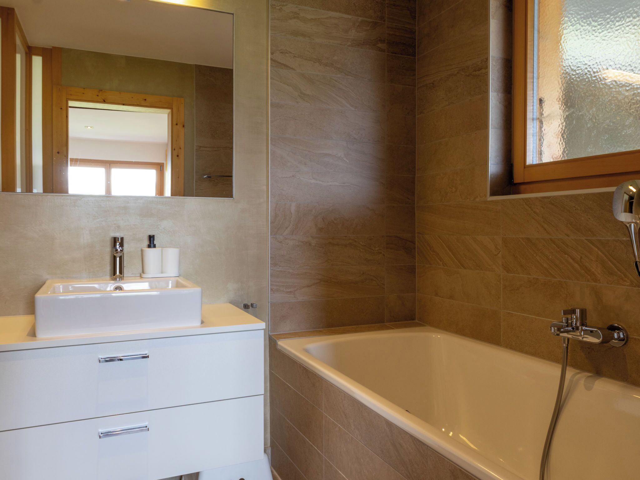 A bathroom with a white sink, mirror, and bathtub.