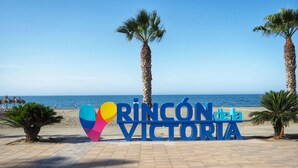 A beachside sign with palm trees and a clear blue sky. - Zurbarán by the Sea by Interhome (Rincón de la Victoria)