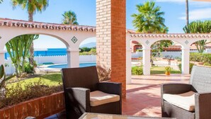 An outdoor patio with wicker furniture, a glass table, and a view of the ocean. - Zurbarán by the Sea by Interhome (Rincón de la Victoria)
