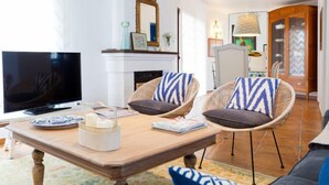 A living room with a television, wicker chairs, a fireplace, and a mirror. - Zurbarán by the Sea by Interhome (Rincón de la Victoria)