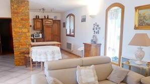 A living room with a beige sofa, a stone pillar, wooden cabinets, a dining table with a white tablecloth, and a large mirror. - La Péguière by Interhome (La Cadière d'Azur)