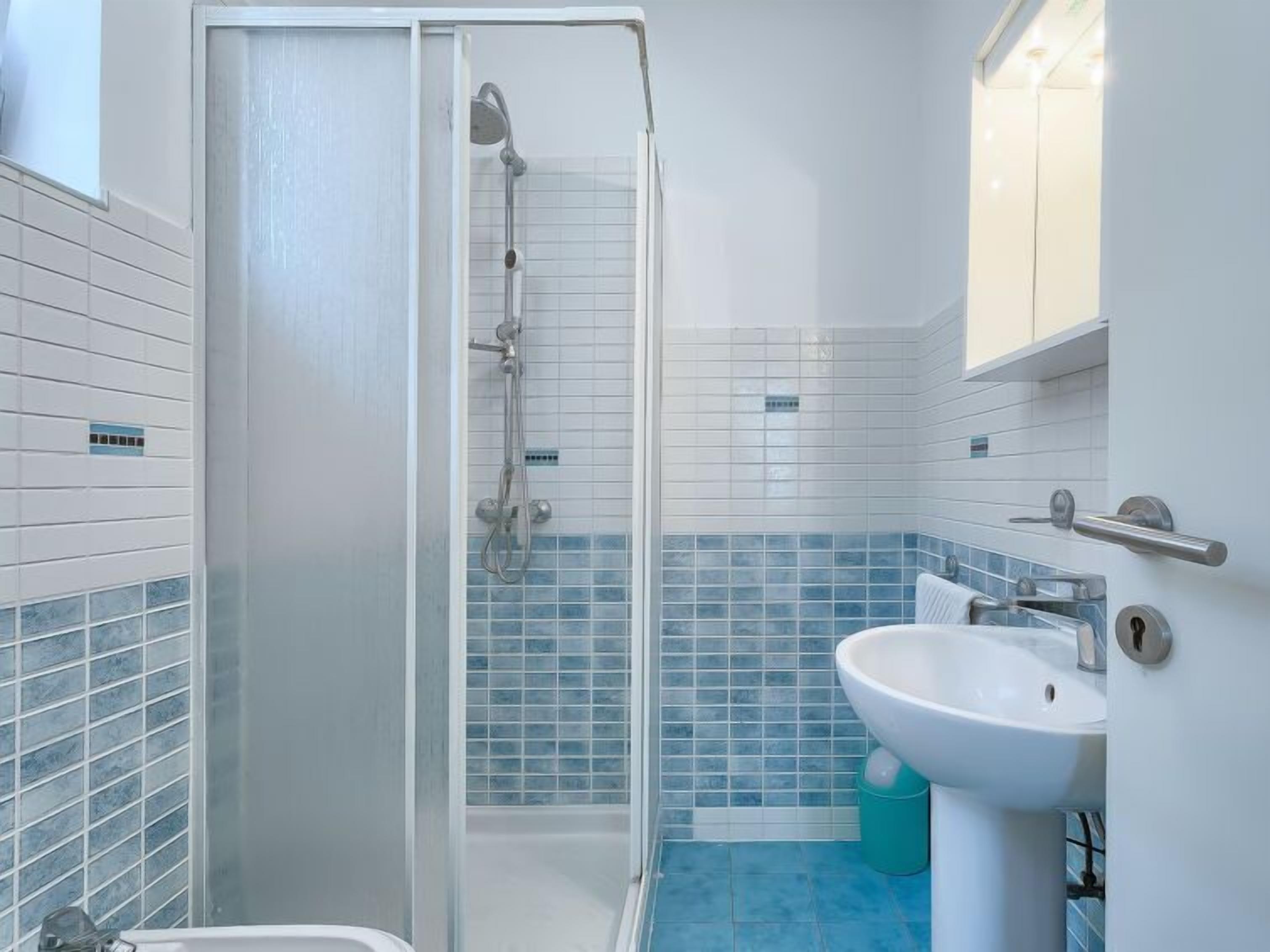 Een badkamer met een douche, wastafel en toilet.
