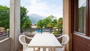 Un balcón con mesa y sillas, con vistas a una piscina y montañas.
