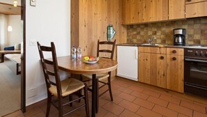Cocina compacta con armarios de madera, un refrigerador pequeño y una cafetera.