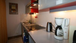 Een kleine keuken met een roestvrijstalen spoelbak, een waterkoker en een koffiezetapparaat.