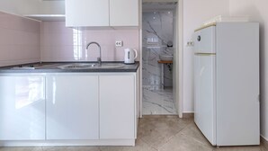 Een moderne keuken met witte kasten, een spoelbak en een koelkast.