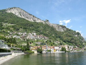 A hillside town with buildings nestled against a rocky cliff, overlooking a calm body of water. - Vacation home Risi by Interhome (Musso)
