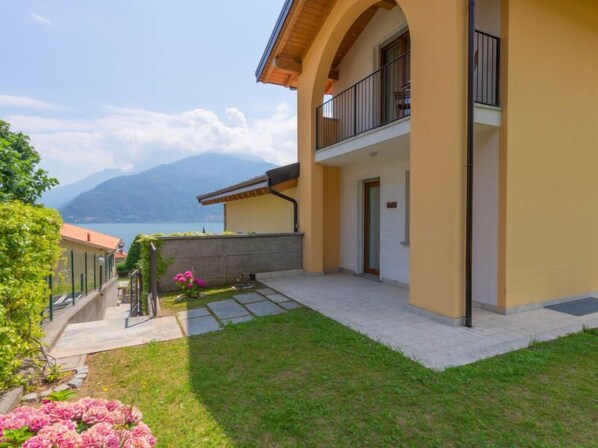 A two-story house with a balcony, a stone pathway, and a view of a lake and mountains. - Vacation home Risi by Interhome (Musso)