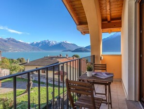 A balcony with a wooden table and chairs, overlooking a lake and mountains. - Vacation home Risi by Interhome (Musso)