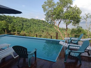 Een buitenzwembad, parasols bij het zwembad en ligstoelen