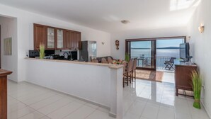 A modern apartment with a kitchen, dining area, and a balcony with a sea view.