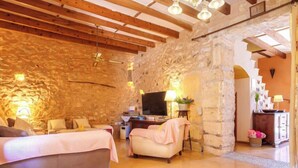 Una stanza accogliente con un letto, un divano, una TV e un muro in pietra.